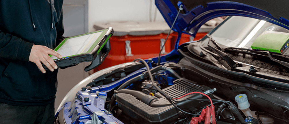 Kfz-Diagnosegerät im Test: Eine Person nutzt ein Kfz-Diagnosegerät bei offener Motorhaube.