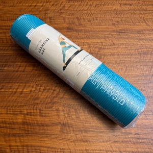 Die Kg-Physio-Yogamatte liegt in ihrer Verpackung auf einem Holztisch