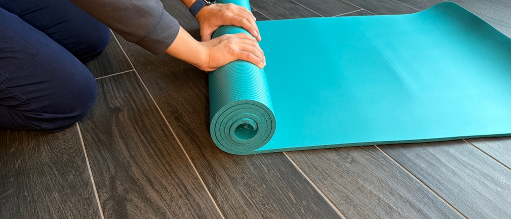 Eine Person rollt die Kg-Physio-Yogamatte zusammen