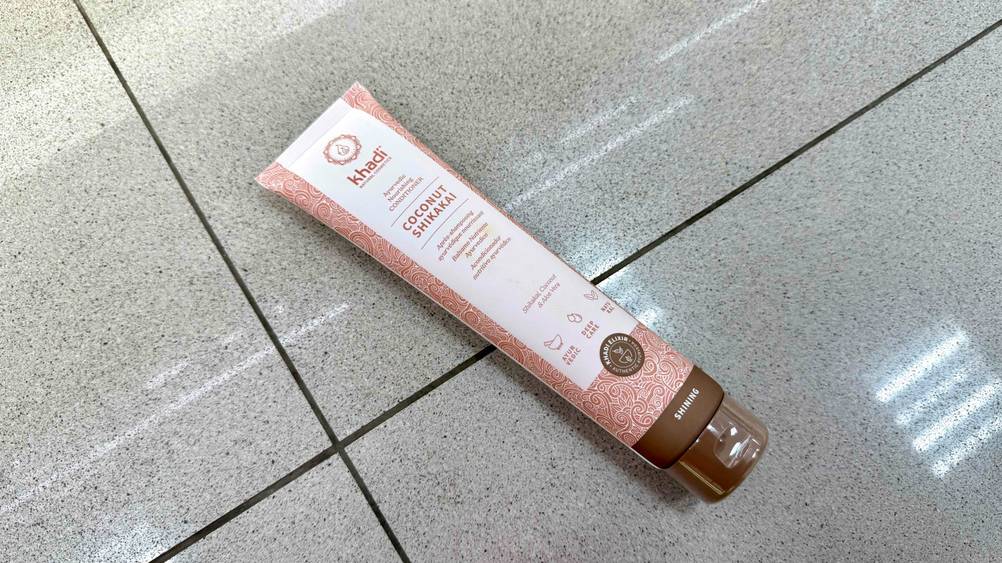 Auf dem Boden liegt leicht horizontal eine Tube des Khadi-Shampoos im Test.