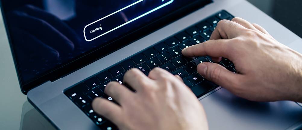 KI-Video-Generator-Test: Eine Person sitzt am Laptop und tippt einen Prompt in eine KI-Software.