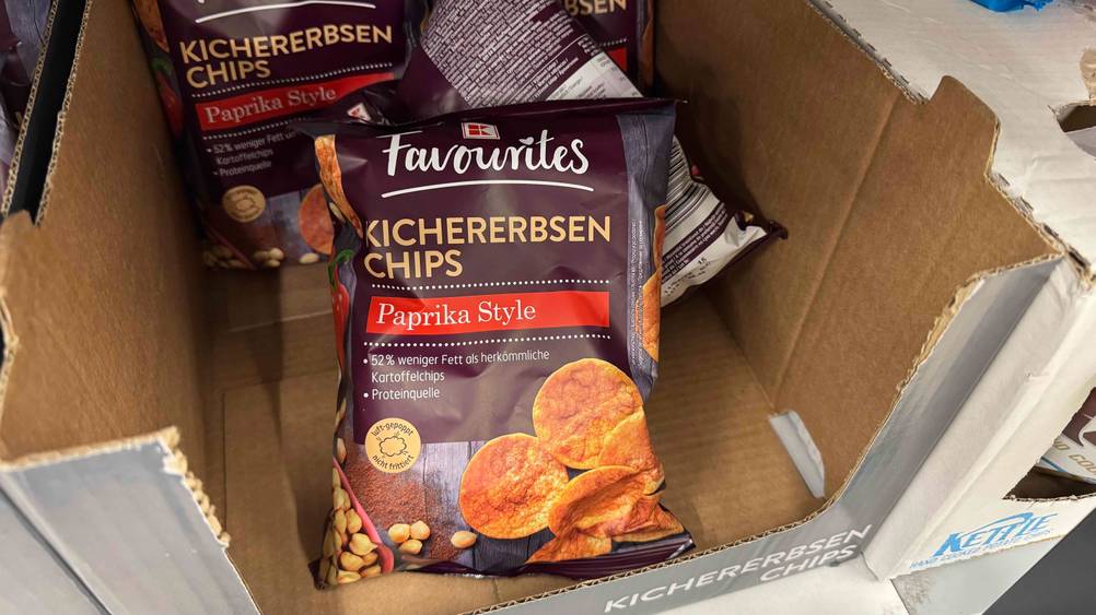 In einem Karton liegen mehrere Packungen der Kichererbsen-Chips im Test.