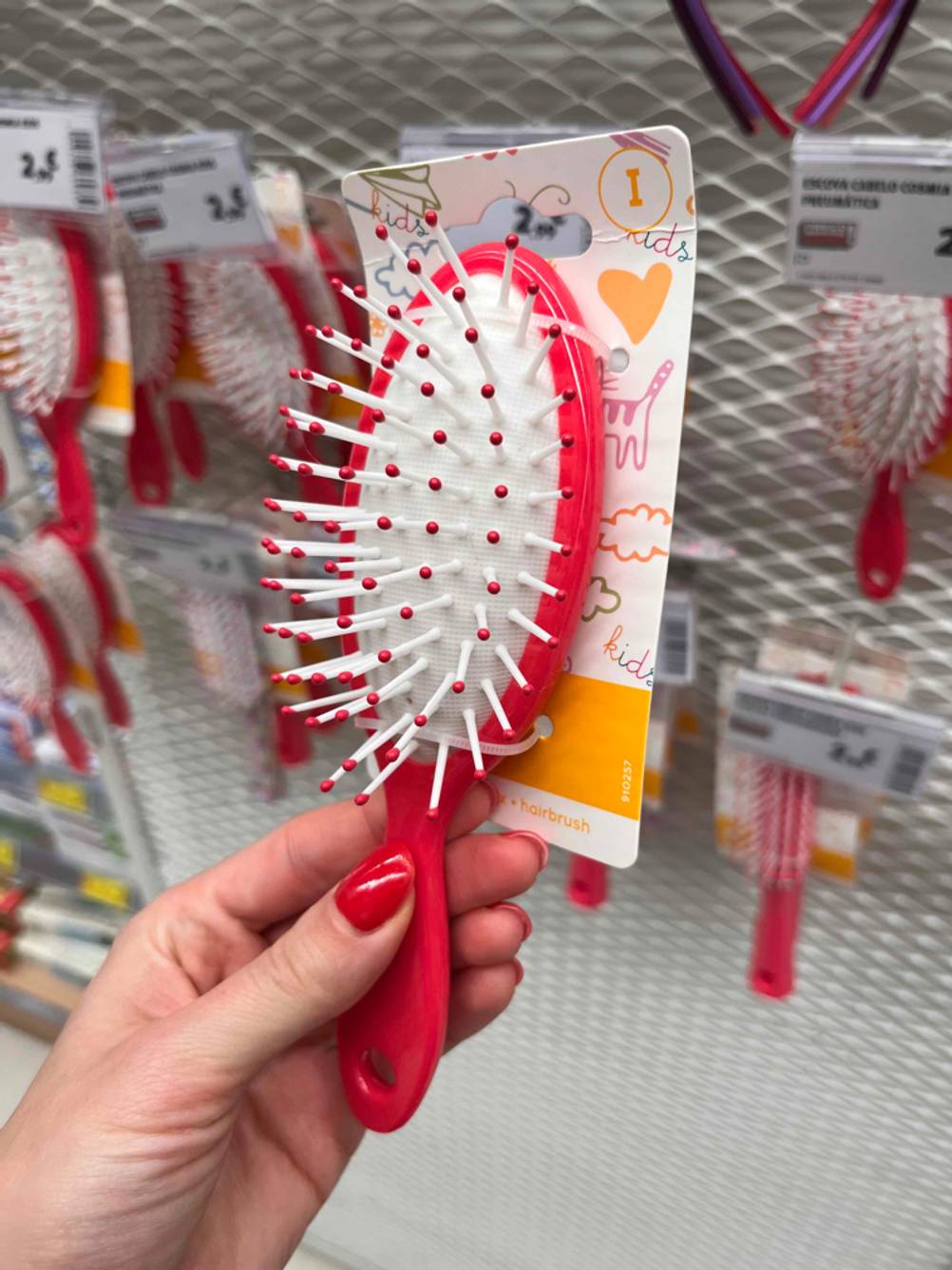 Hand hält eine verpackte rote Kinderbürste zum testen.