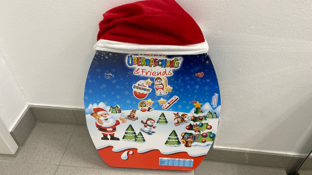 Ein getesteter Kinder-Adventskalenders mit Nikolaus-Zipfelmütze aus rotem Plüsch mit weißem Rand steht auf dem Boden.