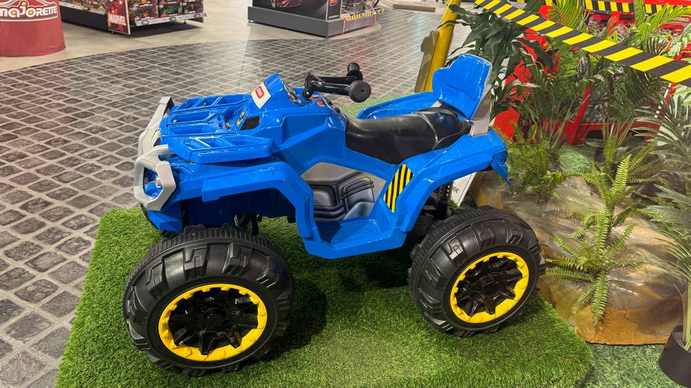 Ein getestetes Kinder-Elektro-Quad von der Seite auf einem Kunstrasen in einer Verkaufsfläche.