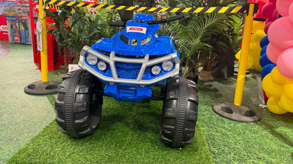 Ein Kinder-Elektro-Quad im Test von vorne vor Pflanzen auf einem Kunstrasen.
