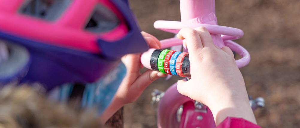 Fahrradschloss für Kinder im Test: Mädchen öffnet ein Zahlen-Fahrradschloss für Kinder.