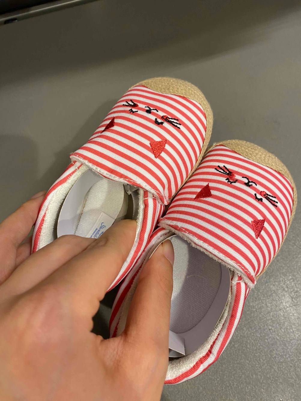 Eine Hand hält ein Paar getestete Hausschuhe für Kinder.