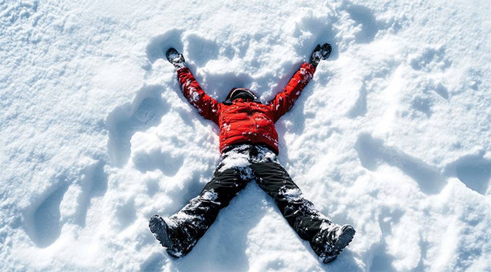 Kinder-Schneehose (Jungen) im Test: Ein Junge in Schneehose und Jacke der einen Schneeengel macht