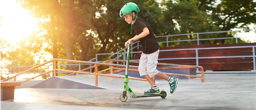 Kinder-Scooter im Test: Ein Junge, der mit einem grünen Kinder-Scooter fährt.