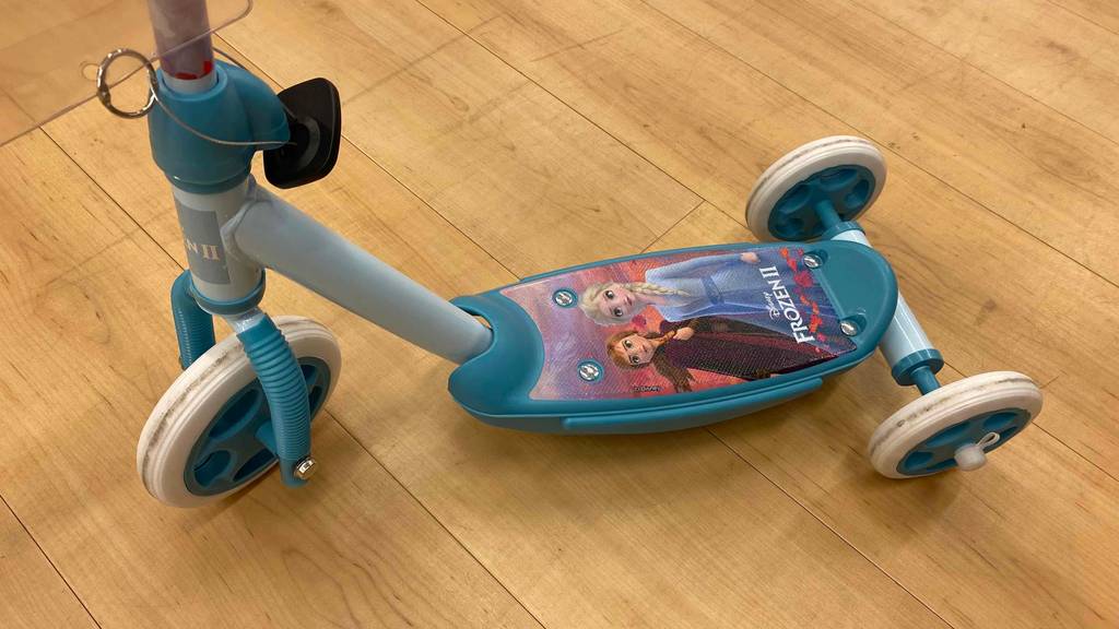 Ein getesteter Kinder-Scooter mit Disney-Motiven steht auf einem Holzboden. 