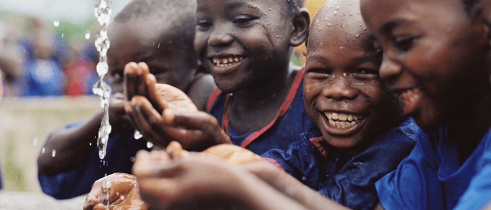 Kinder in Sierra Leone freuen sich über Wasser. Foto: Plan