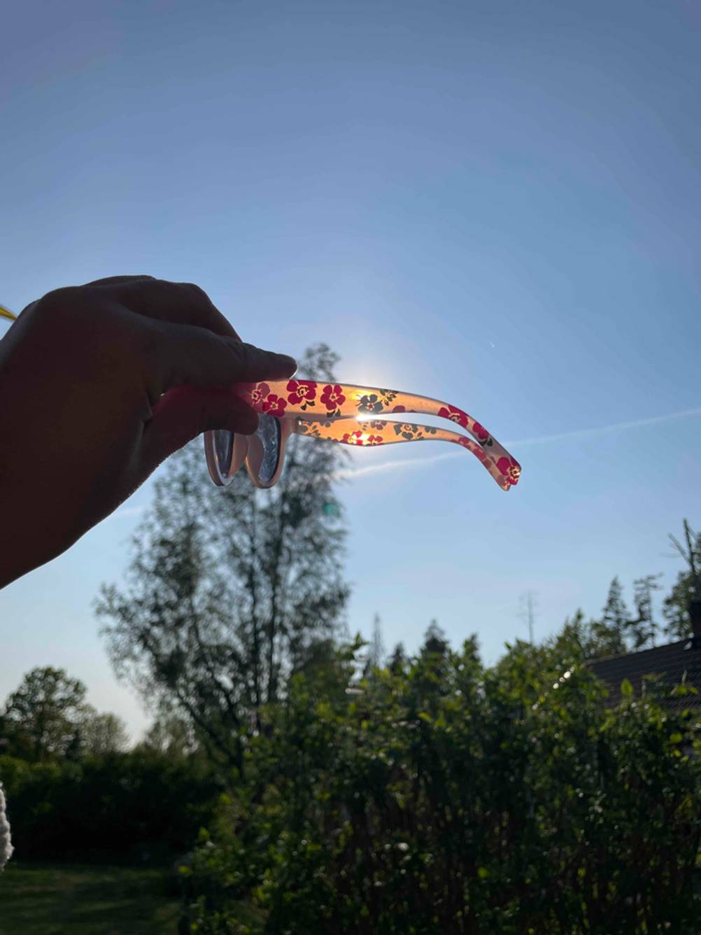 Eine Kinder-Sonnenbrille wird vor die Sonne gehalten.