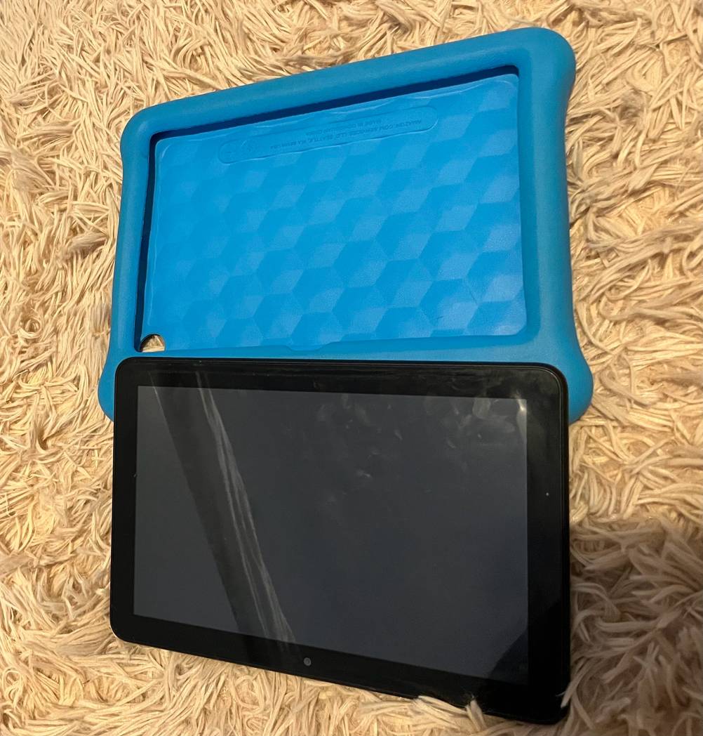 Ein getestetes Kinder-Tablet liegt leicht über seiner Hülle auf einem Teppich.