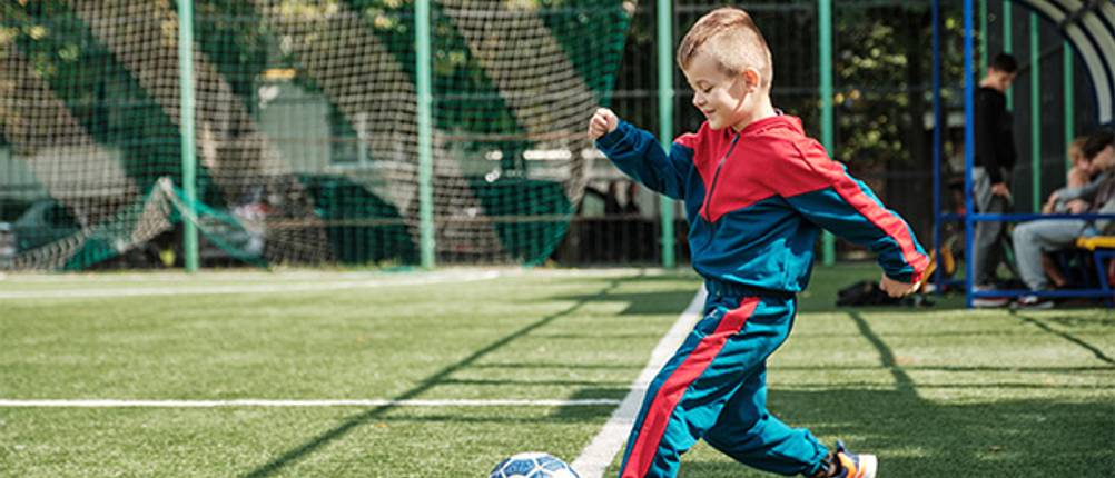 Kinder-Trainingsanzug im Test: Ein Junge im Trainingsanzug der Fußball spielt.