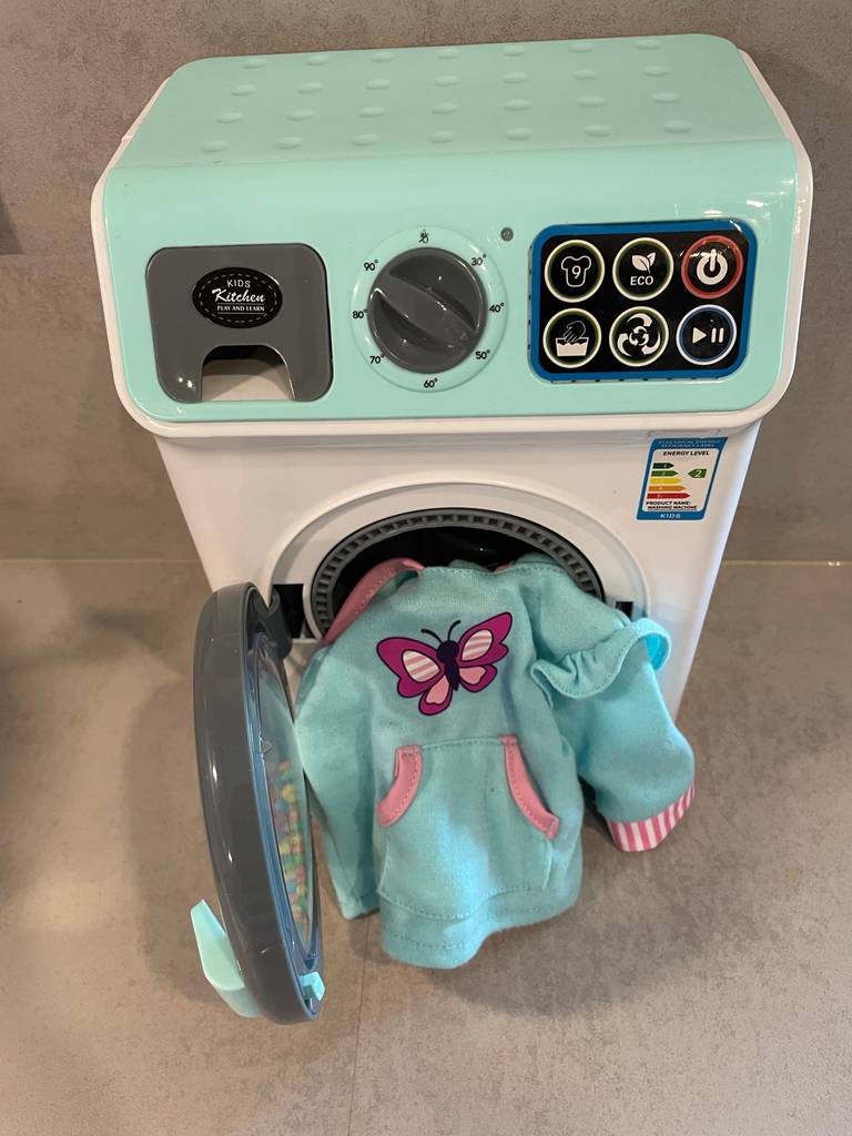 Ein Pullover hängt aus einer getesteten Kinder-Waschmaschine heraus. 