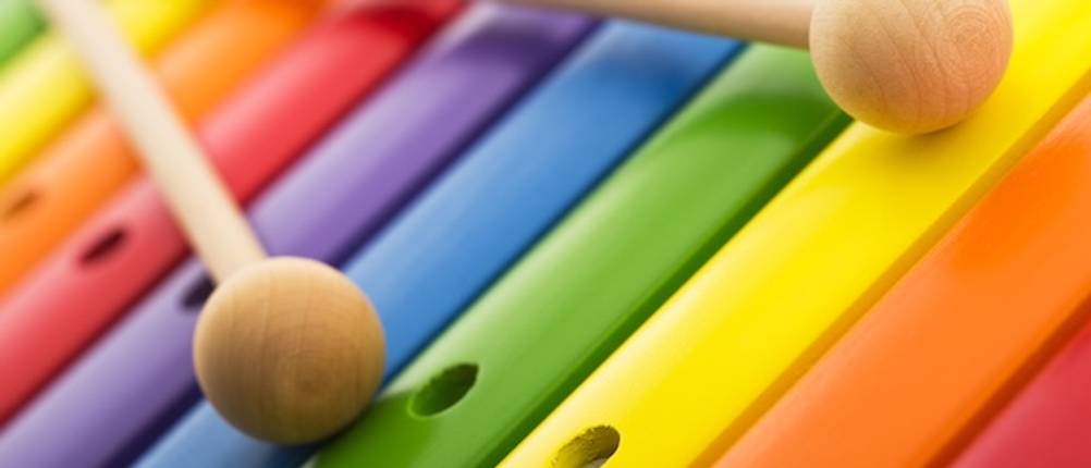 Kinder-Xylophon-Test: Nahaufnahme von zwei Schlägeln auf bunten Klangstäben eines Kinder-Xylophons.