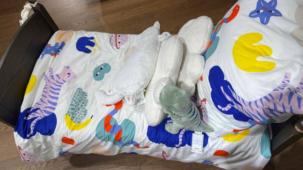Die getestete Kinderbettwäsche auf ein Bett bezogen mit Kuscheltieren.