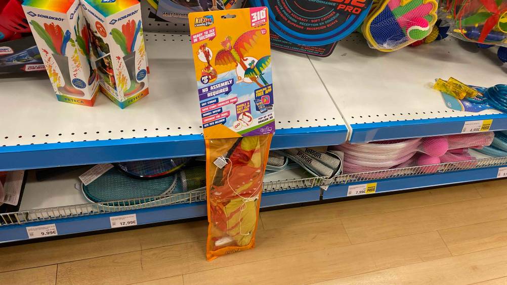 Getesteter Kinderdrachen mit verschiedenen Farben liegt an einem Geschäftsregal an.