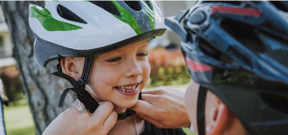 Einem Kind wird der Fahrredhelm verschnallt