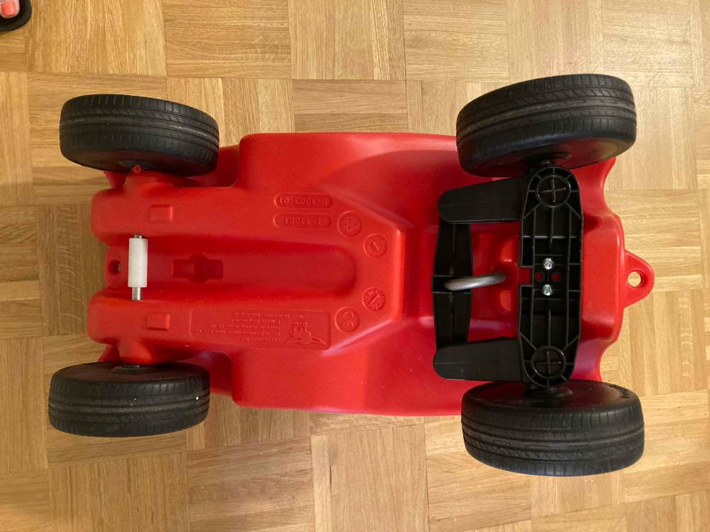Das getestete Kinderfahrzeug von unten auf einem Holzboden liegend.