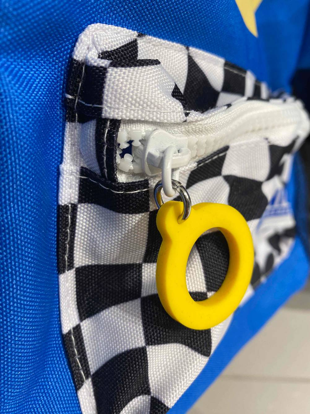 Kindergartenrucksack getestet: Nahaufnahme des gelben, runden Zippers an der Vordertasche.