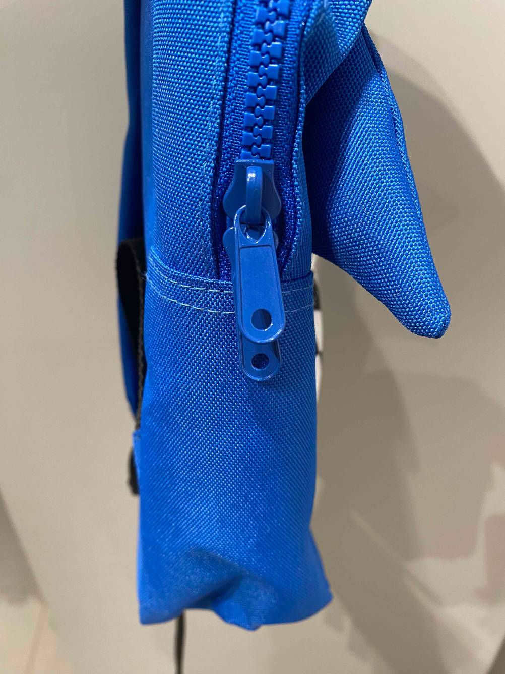 Nahaufnahme der Reisverschlusszipper an einem blauen Kindergartenrucksack.
