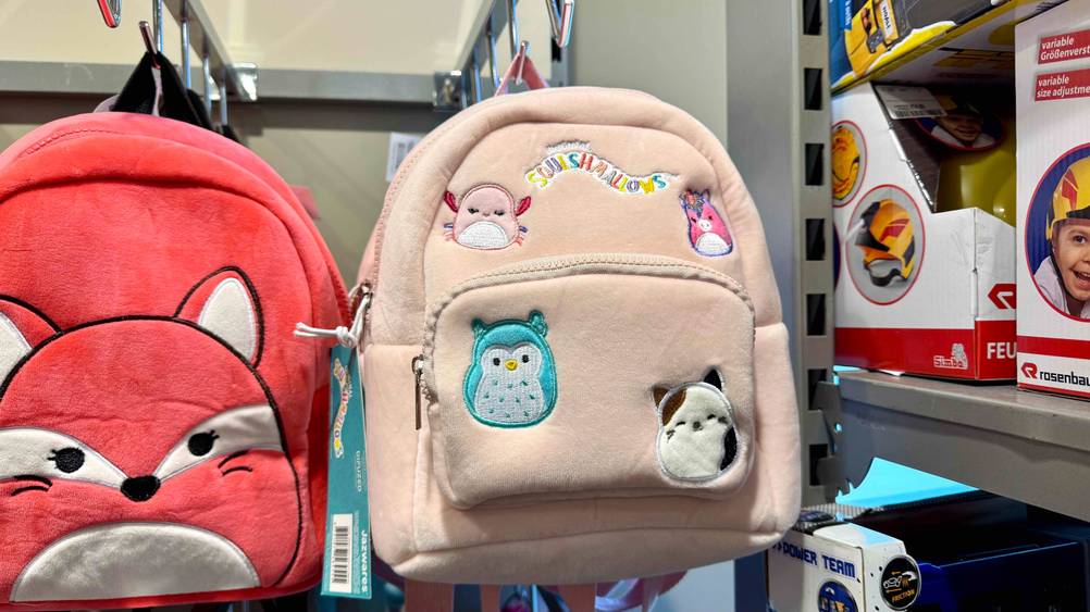 Ein getesteter Kindergartenrucksack Mädchen hängt in einem Verkaufsregal neben anderen Produkten.
