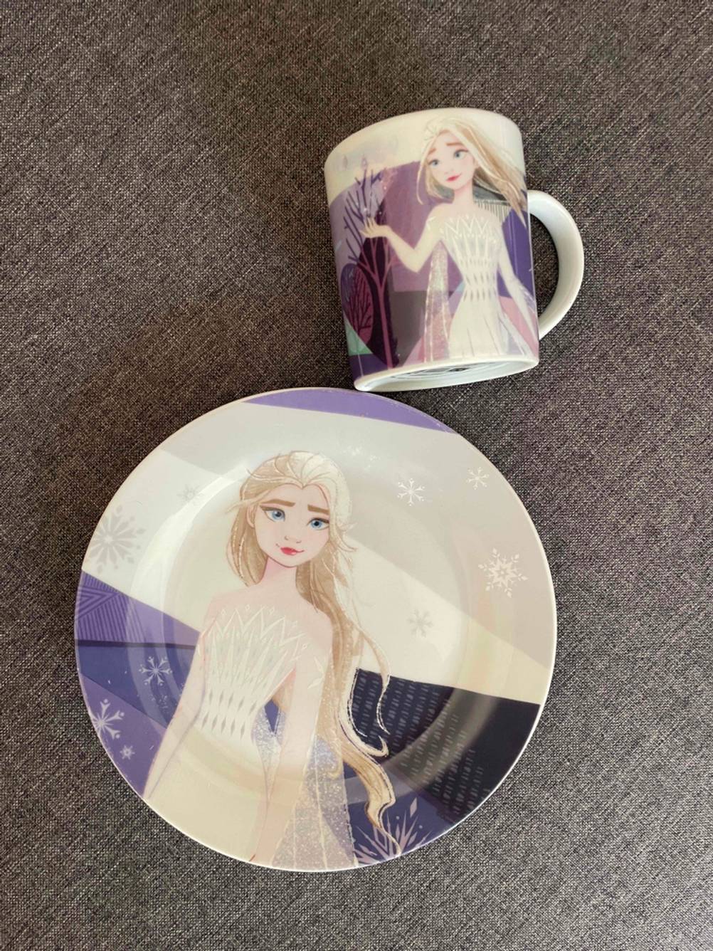 Kindergeschirr getestet: Ein Teller und eine Tasse auf einer grauen Fläche.
