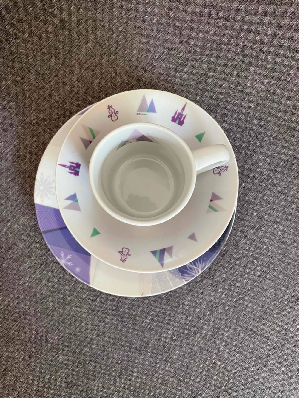 Ein Kindergeschirr im Test von oben mit Teller, Schüssel und Tasse.