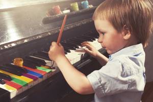 Young boy painting piano keys with brush. True art