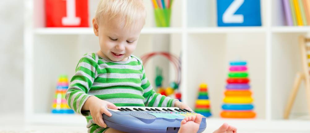 Kinderkeyboard für Kleinkinder im Test: Ein kleiner Junge sitzt im Kinderzimmer auf dem Boden und spielt ein blaues Keyboard.