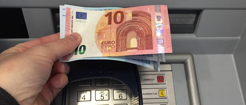 Eine Person hebt Bargeld am Bankautomaten ab.