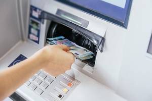 Kinderkonten im Test: Eine Hand nimmt Geld aus einem Geldautomaten.