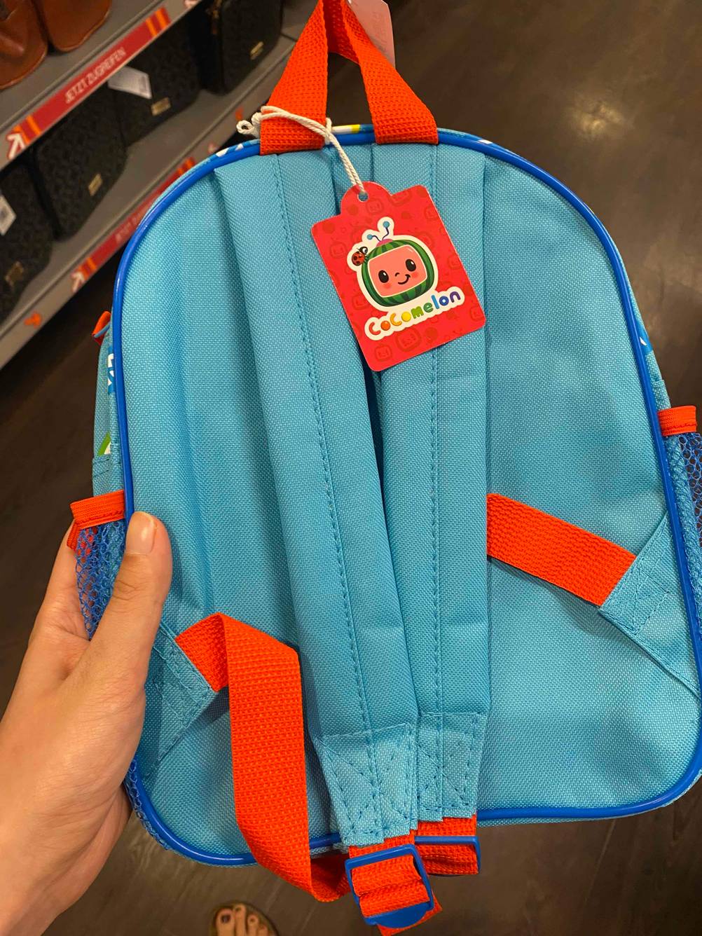 Eine Hand hält einen getesteten Kinderrucksack mit Schultergurten. 