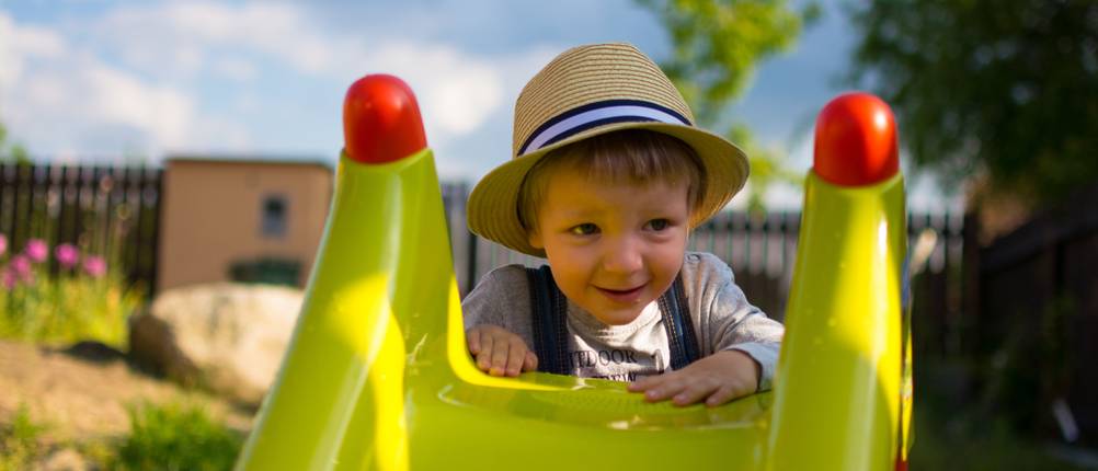 kleinkind hinter kinderrutsche im garten