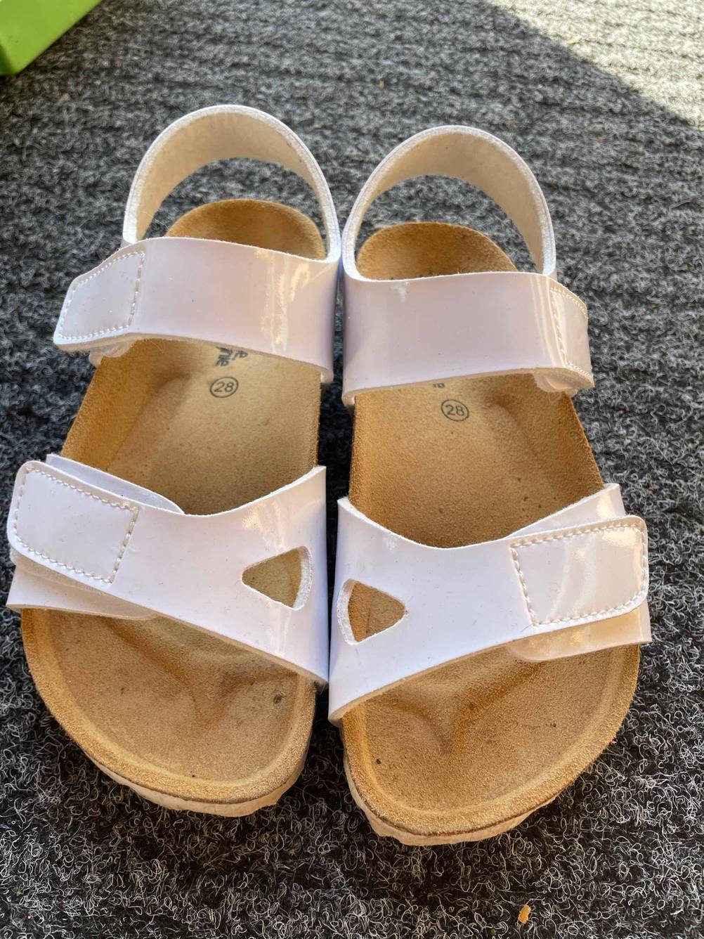 Kindersandalen getestet: Ein Paar Sandalen in rosa auf einem dunklen Teppich.