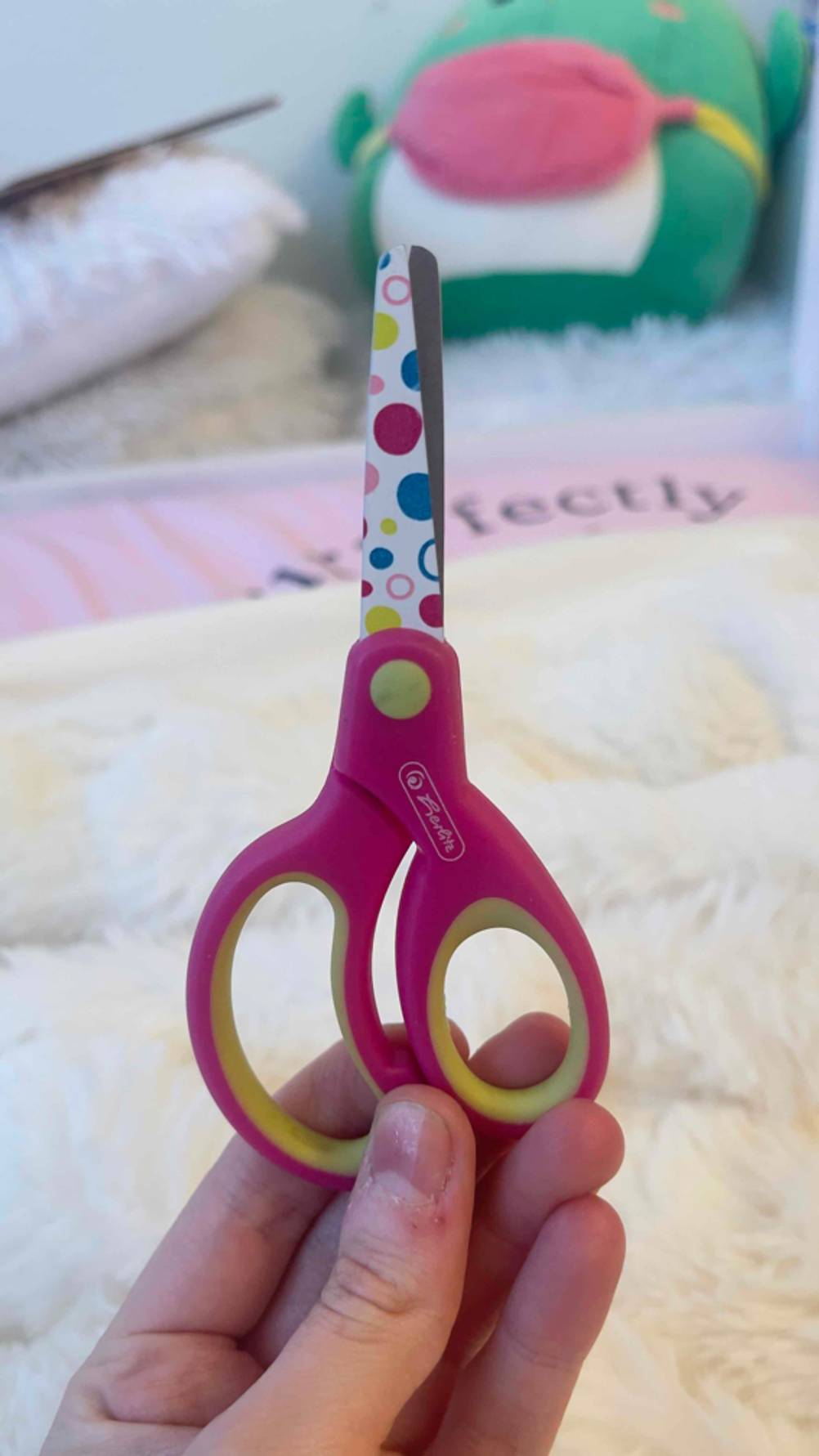 Eine Hand hält eine geschlossene Kinderschere im Test hoch.
