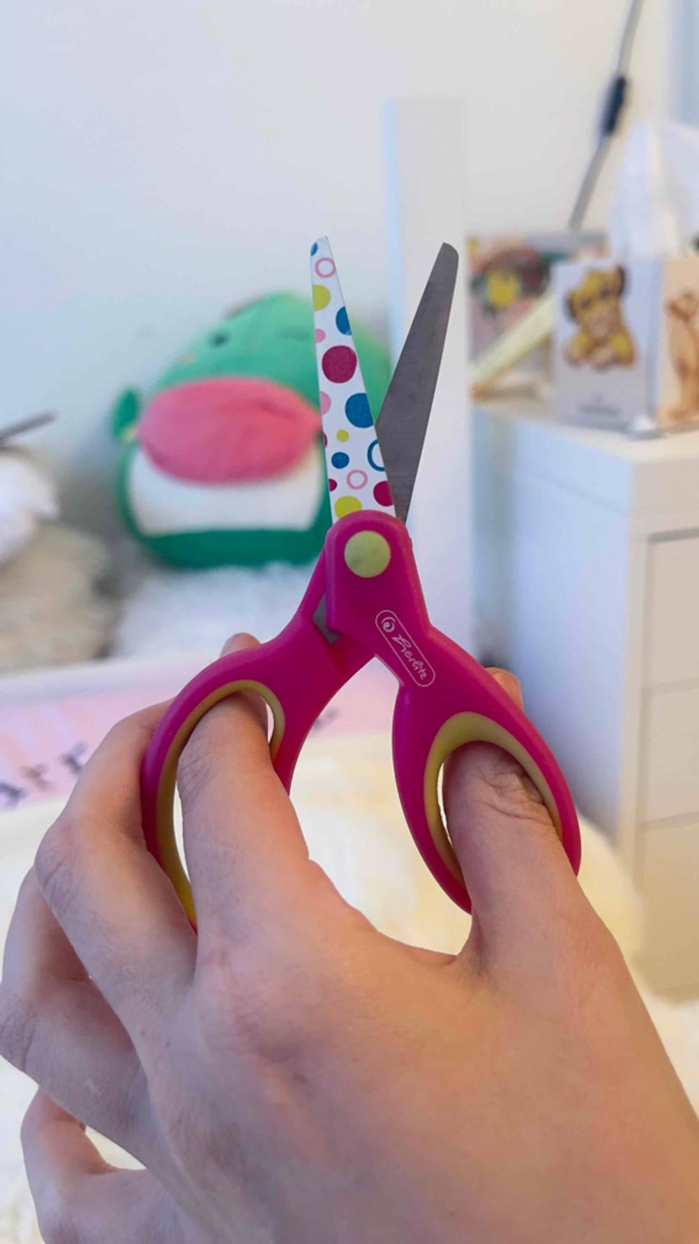 Eine Hand hält eine Kinderschere im Test hoch.