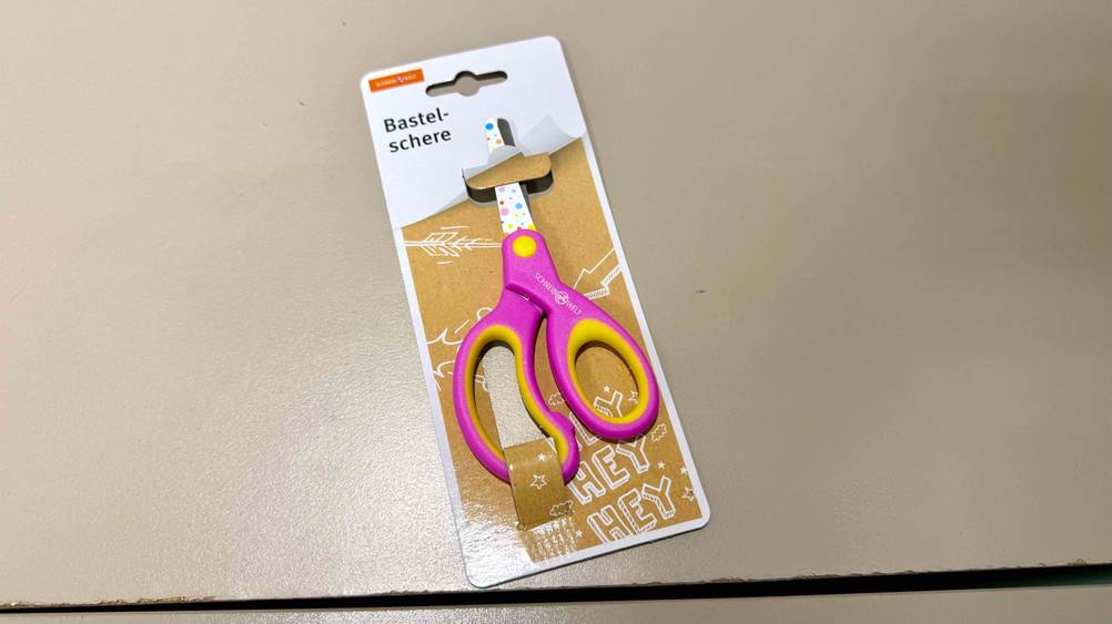 Auf einer hellen Fläche befindet sich eine Kinderschere im Test.