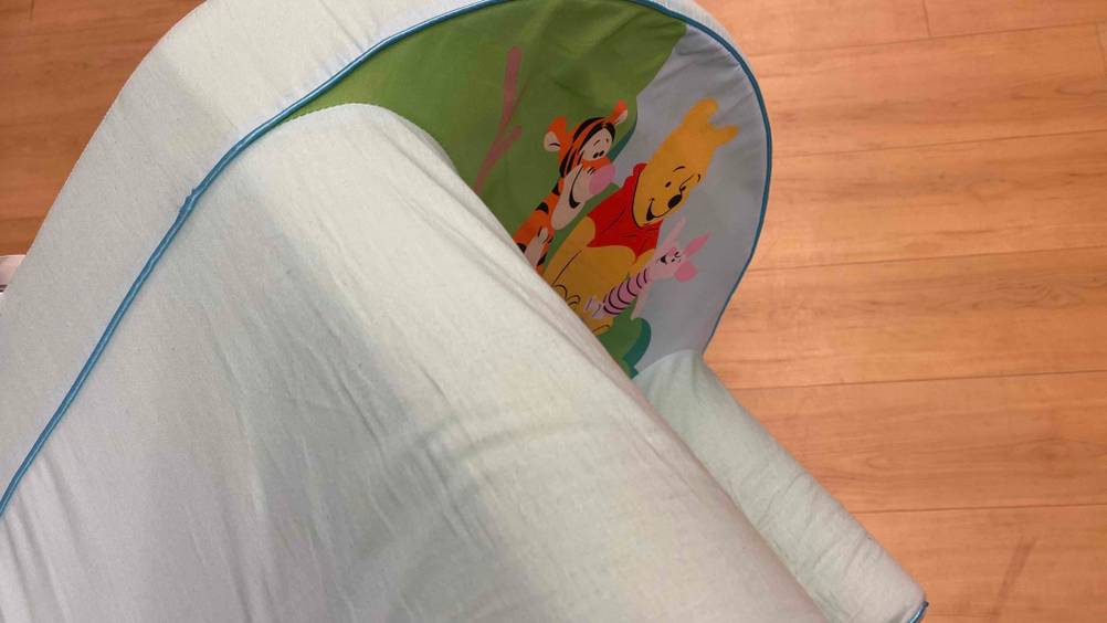 Ein Kindersessel im Test liegt mit der Unterseite nach oben auf einem Holzboden.