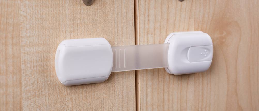 Kindersicherung Schrank Test: Weiße Kindersicherung an Holzschrank
