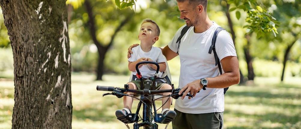 Kindersitz Fahrrad (vorne) im Test: Ein Mann, der einen kleinen Jungen im Fahrradsitz vorne platziert hat.