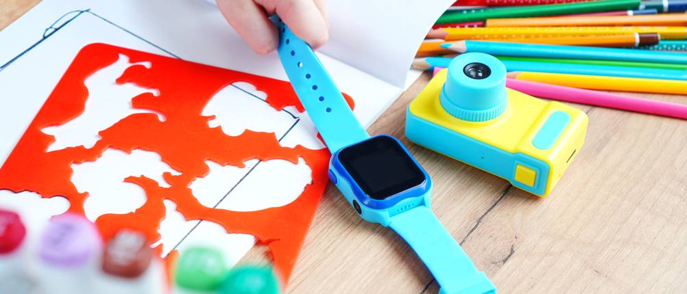 Kinderuhr mit Telefonfunktion Test: Türkise Kinderuhr mit Stiften und Kinderkamera auf Tisch