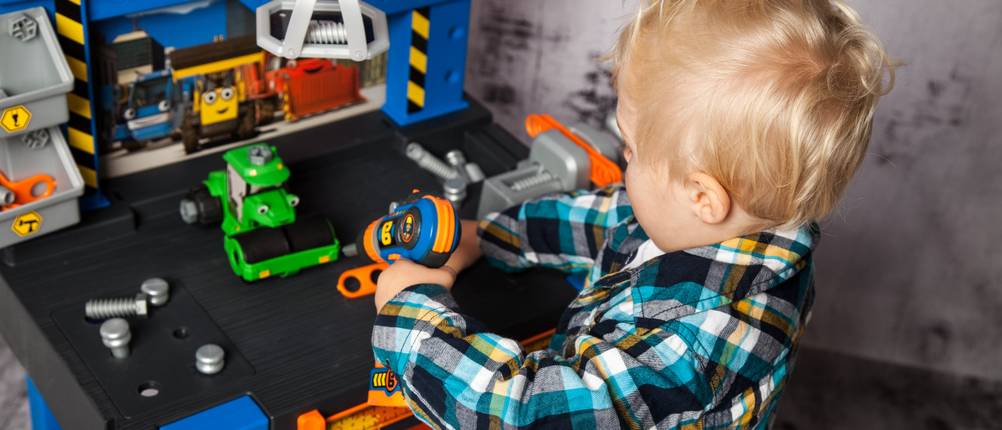 Kinder-Werkbank im Test: Ein kleiner Junge der an einer Werkbank aus Kunststoff schraubt.