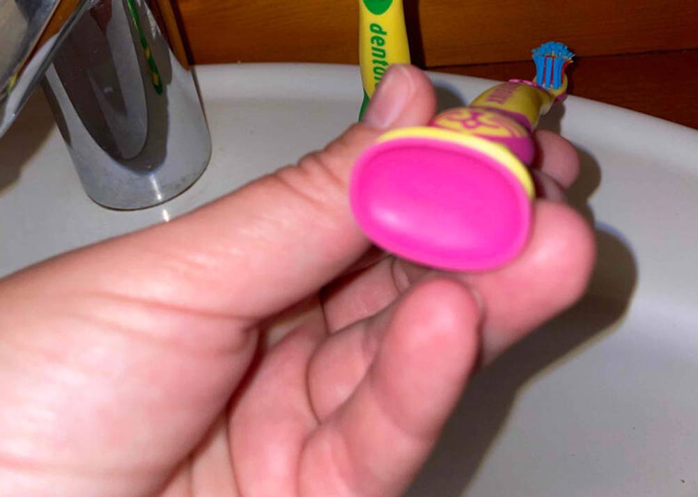 Nahaufnahme des Saugnapfes auf der Unterseite einer getesteten Kinderzahnbürste von einer Hand gehalten.