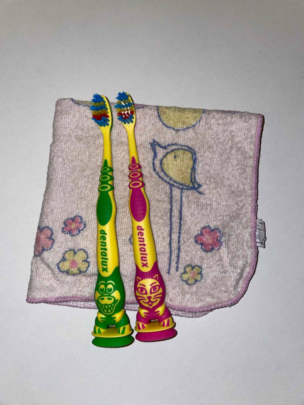 Zwei getestete Kinderzahnbürsten liegen auf einem dünnen Handtuch. 
