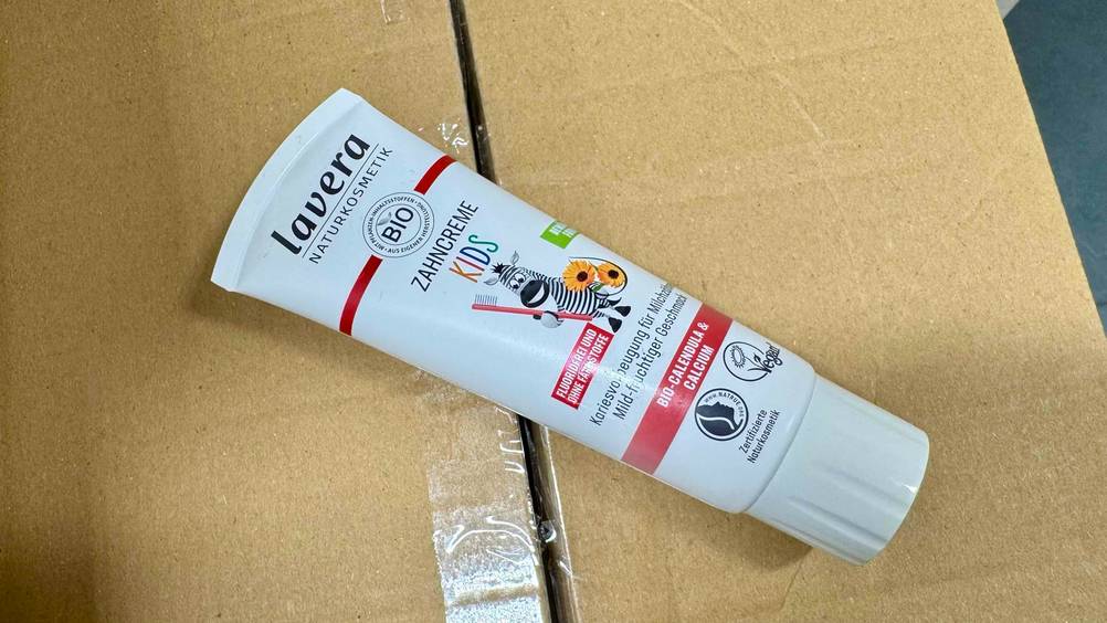 Eine Tube der Kinderzahnpasta ohne Fluorid im Test auf einem Karton.