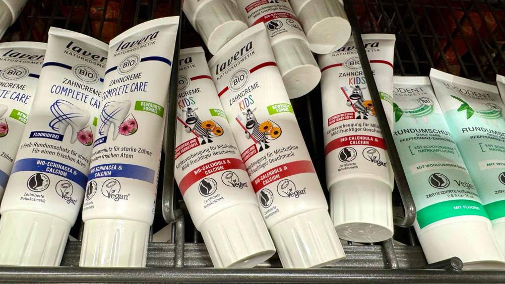Kinderzahnpasta ohne Fluorid getestet: Mehrere Tuben in einem Regal neben anderen Produkten.