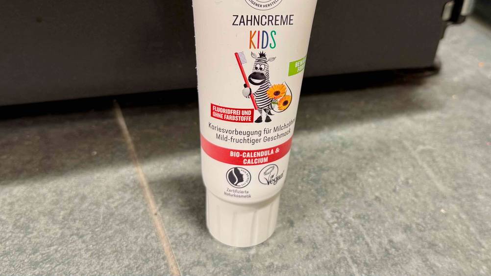Kinderzahnpasta ohne Fluorid-Test: Nahaufnahme der Verschlusskappe und der Informationen auf der Packung.